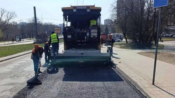 Асфальтоукладач кладе нове покриття на міській вулиці біля зупинки, ілюстративне фото